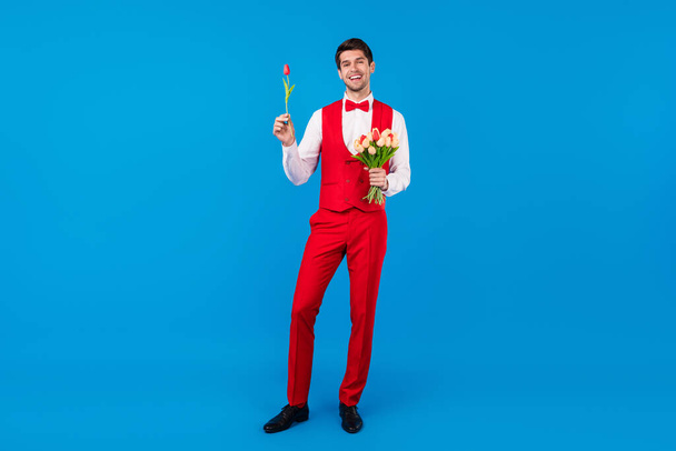 Full body photo of young handsome man happy positive gentleman present flower isolated over blue color background - Foto, Bild