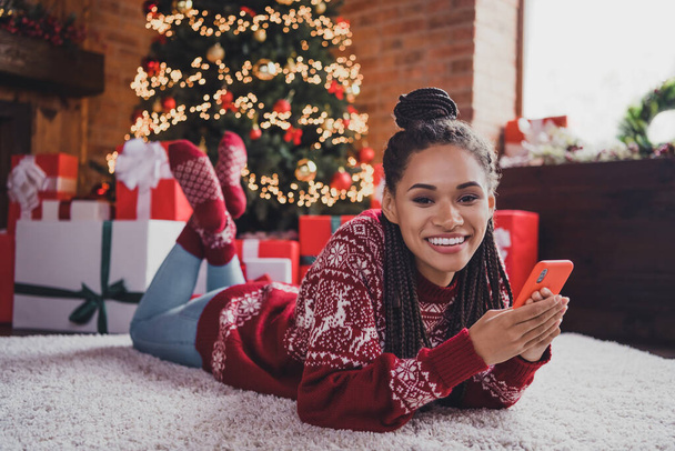 Photo of dreamy pretty blogger lady hold telephone make social media x-mas post wear jumper in decorated home indoors - Фото, зображення