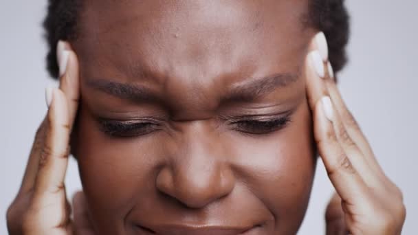 Vérnyomás és fejfájás. Közelkép a depressziós fiatal afro-amerikai nőről, aki a fájó halántékát masszírozza. - Felvétel, videó