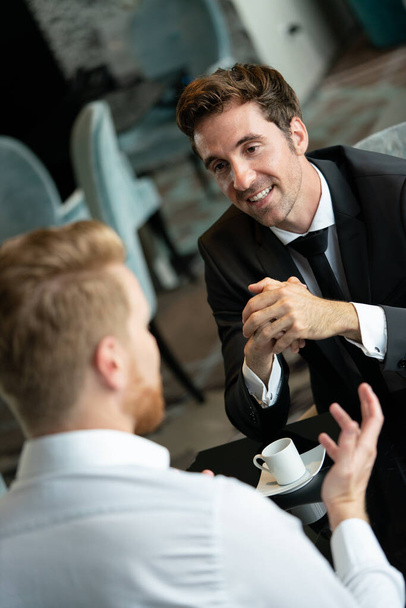 Image of young businessman with cup of coffee communicating with his colleague - Fotografie, Obrázek