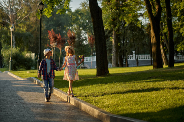 Childrens date, boy and girl on walk path in park - Fotó, kép