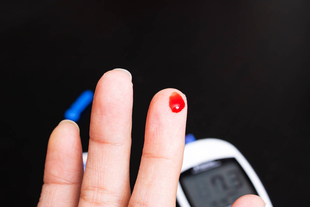 Підвищений рівень цукру в крові на моніторі глюкометра і палець з кров'ю
 - Фото, зображення