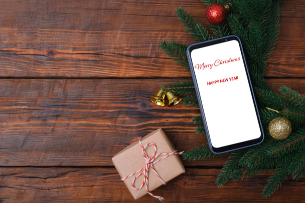 Smartphone moderne avec maquette sur table vintage en bois avec décoration de Noël, coffret cadeau. Gabarit plat. Couronne de sapin - Photo, image