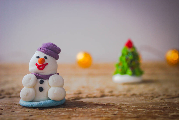 Christmas decor. A miniature figure of powdered sugar snowman with a purple hat stands on a wooden board. - Foto, Imagem