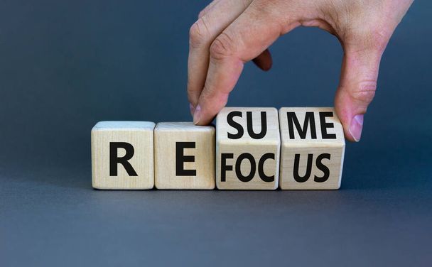 Refocus and resume symbol. Businessman turns cubes and changes the word 'refocus' to 'resume'. Beautiful grey table, grey background. Business refocus and resume concept. Copy space. - Фото, изображение