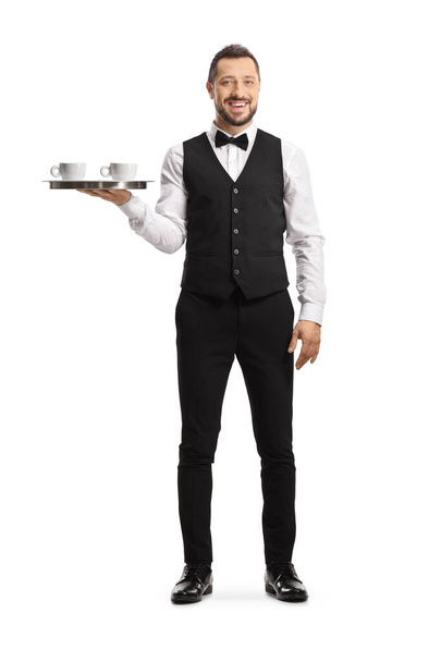 Full length portrait of a smiling server holding a tray with coffee cups isolated on white background - Φωτογραφία, εικόνα