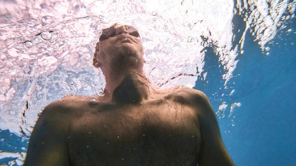 Man in bril in het blauwe en transparante water van de Middellandse Zee. De camera vasthouden - Foto, afbeelding