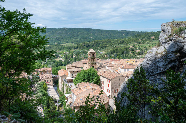Blick auf Bergklippen, alte Häuser, grünes Tal im abgelegenen mittelalterlichen Dorf Moustiers-Sainte-Marie in der Provence, Frankreich. Touristisches Ziel. - Foto, Bild