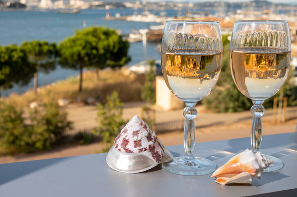 Nyár a francia Riviérán, hideg fehér vagy rózsa gris bor fogyasztása Cotes de Provence-ból szabadtéri teraszon, kilátással Toulon, Var, Franciaország kikötőjére és tengeri kagylókra - Fotó, kép