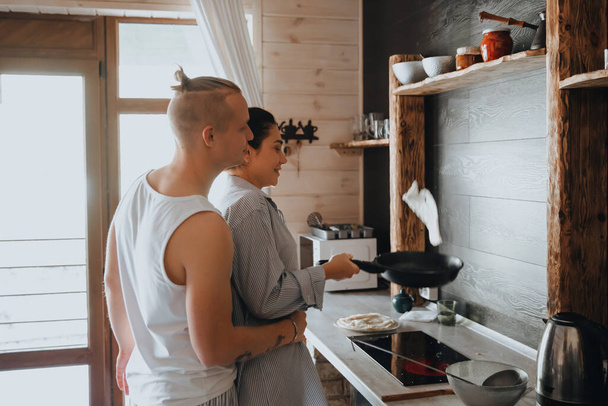 Любящие пары готовят еду вместе, наслаждаясь приготовлением пищи, стоя на кухне. - Фото, изображение