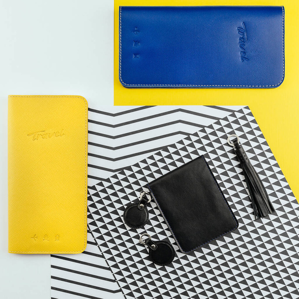 Yellow and blue leather travel purses for holding passport, money, boarding pass or id. Black holder for driver's license or documents and several key chains. Flat lay. Vacation and tourism concept. - Φωτογραφία, εικόνα