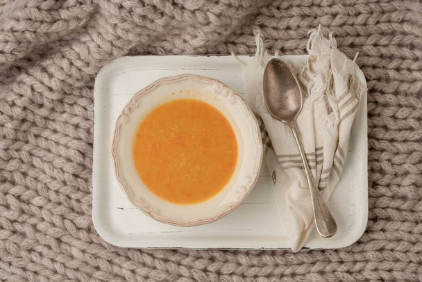 bowl of pumpkin soup on a white tray on the bed covered with blanket in winter - Foto, afbeelding