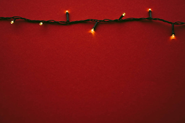 Red background with illuminated lights of garland - Φωτογραφία, εικόνα