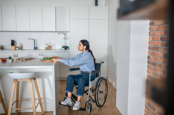 A cute girl on a wheelchair in the kitchen at home - Foto, immagini