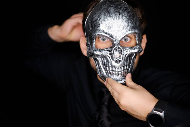 a man wearing a skeleton mask, he corrects it with his hands - Foto, Imagen