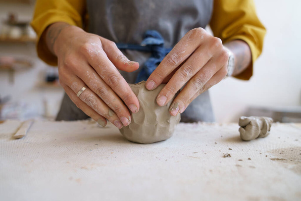 Ellerinizle çalışın: Sanatçı kadın, çömlek ya da seramik şekillendirmek ve şekillendirmek için işlenmemiş kil kullanıyor. - Fotoğraf, Görsel