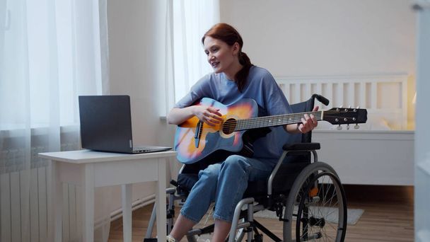 障害者の女性がギターを弾いて歌を歌っている - 写真・画像