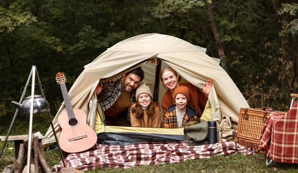Heureux père de famille, mère et deux petits enfants assis dans la tente au camping en forêt - Photo, image