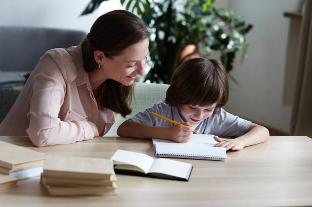A happy mom shows and tells her son how to solve a difficult math example and learn to count and multiply. - Photo, Image