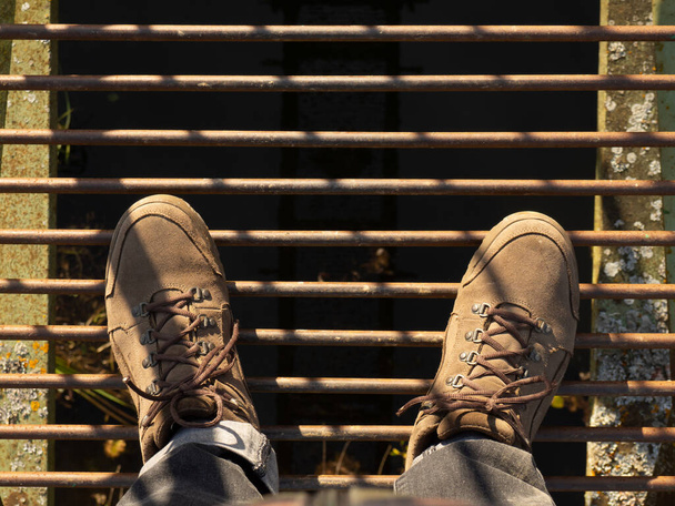 zamszowe buty widok z góry stanąć na żelaznym moście nad przepaścią - Zdjęcie, obraz