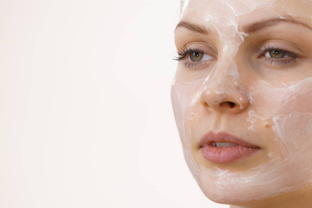 Young woman with cream cosmetic, mask moisture on her face. Beauty treatment. Skincare. Text area - Foto, Imagen