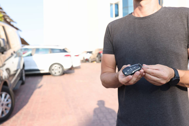 Man houdt in handen drukknop afstandsbediening van auto closeup - Foto, afbeelding