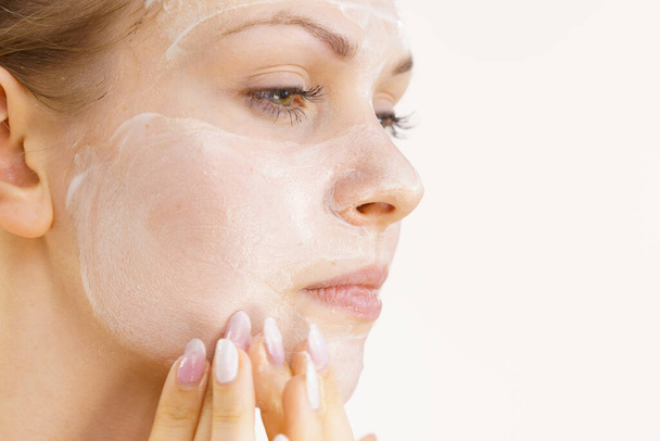 Young woman applying cream cosmetic, mask moisturizing to her face. Beauty treatment. Skincare. - Foto, Imagem