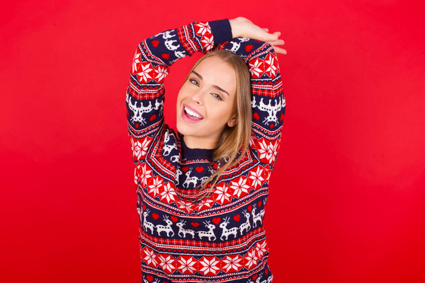 young caucasian girl wearing christmas sweater stretching arms, relaxed position. - Valokuva, kuva