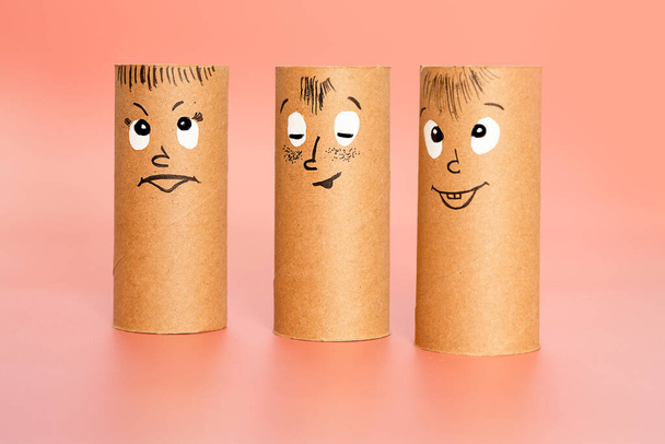 personnages en rouleau de papier toilette avec visage peint exprimant bonheur ou satisfaction sur fond rose, concept de groupe émotionnel, idées bricolage pour l'artisanat avec les enfants - Photo, image