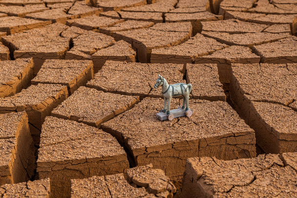 Ló akció figura a kerekek repedt agyag a sivatagban - Fotó, kép