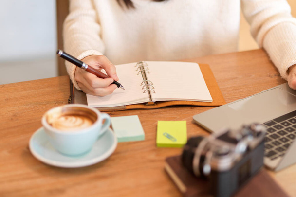 Cropped image of young woman writing her daily routines on her personal diary book at cafe - Photo, Image