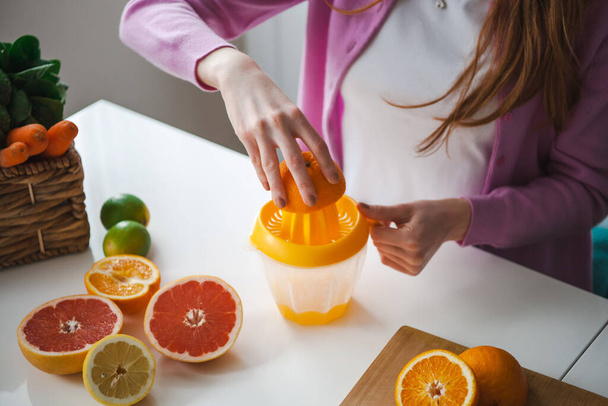Bir meyve suyu dolusu vitamin yapmak için portakal sıkan kadın eli resmi. Sağlıklı beslenme. Meyve suyu.. - Fotoğraf, Görsel