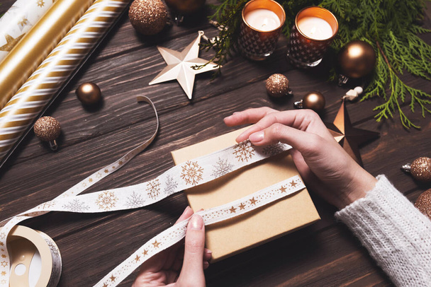 Frauenhände nehmen ein festliches Band zum Einwickeln eines Weihnachtsgeschenks in die Hand. Diy-Hobby. - Foto, Bild