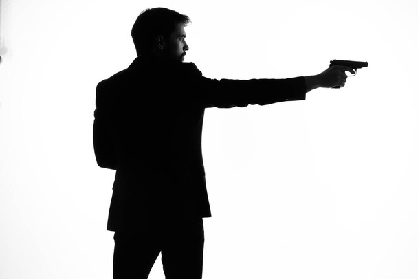 The man in a suit gun in the hands of the emotions silhouette posing studio - Foto, imagen