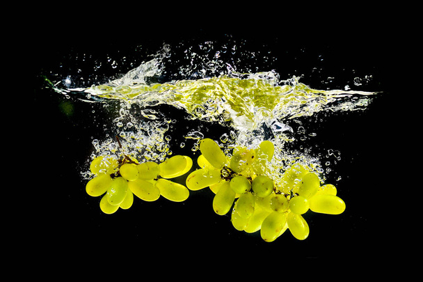 Green grapes in the water are refreshing. on a black background - Φωτογραφία, εικόνα