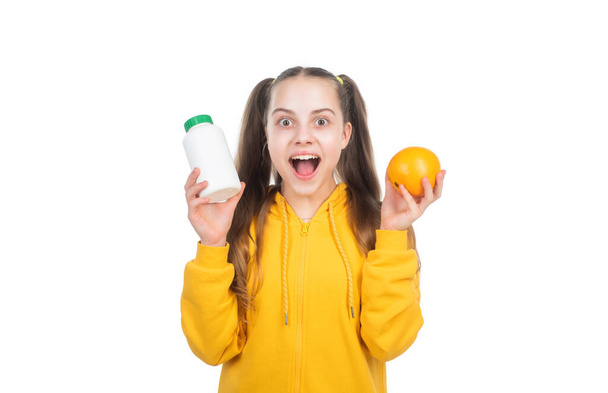 surprised teen girl choose between orange fruit and vitamin pill in jar bottle, healthy nutrition. - Fotoğraf, Görsel