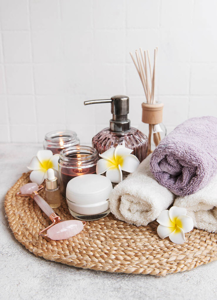 Ensemble spa, huile essentielle, sel de massage, bougie et fleurs frangipani sur fond de béton gris - Photo, image