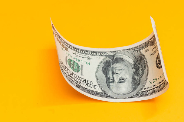 Single Honderd Dollar Bill gekruld op geel - Foto, afbeelding