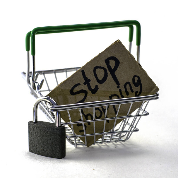 il concetto di rifiuto di acquistare un consumo ragionevole è un carrello con un lucchetto e un cartello che dice stop shopping su uno sfondo bianco. Foto di alta qualità - Foto, immagini