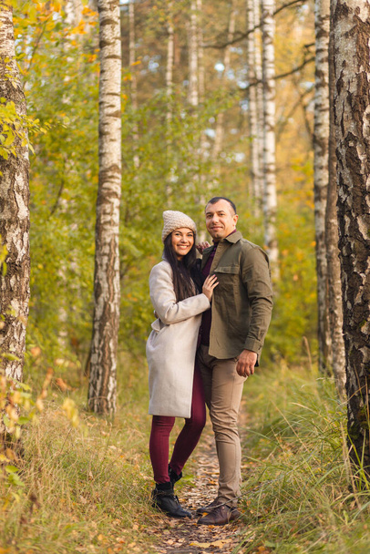 Lovely couple having fun together in nature. A young man and a woman embrace and pose in a birch grove in the golden autumn.. Holidays, love, travel, tourism, relationship and dating concept. - Photo, Image