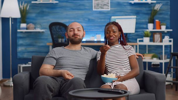 Молода міжрасова пара дивиться фільм по телевізору з попкорном
 - Фото, зображення