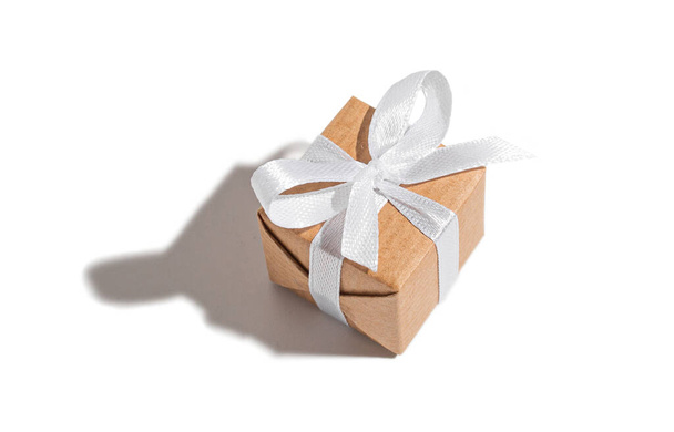 Gift tied with a white ribbon on a white isolated background. Celebration and congratulations holiday concept - Φωτογραφία, εικόνα