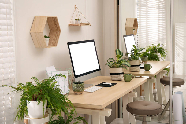 Comfortable workplace with modern computer and houseplants in room. Interior design - Foto, imagen