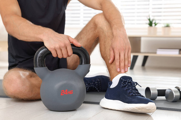 Man with kettlebell on floor at home, closeup - Foto, immagini