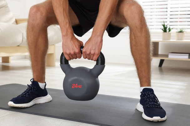 Man training with kettlebell at home, closeup - Foto, imagen
