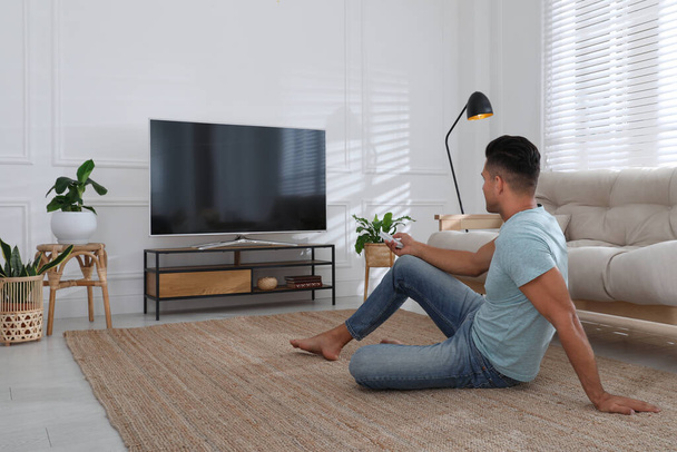 Man watching television at home. Living room interior with TV on stand - Fotoğraf, Görsel