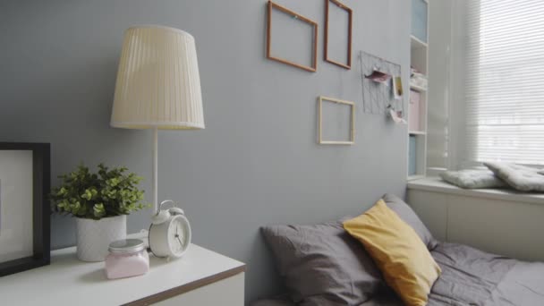 No people slowmo shot of interior design of modern hangulatos hálószoba szürke falakkal, kényelmes ágy és képkeretek a falakon - Felvétel, videó