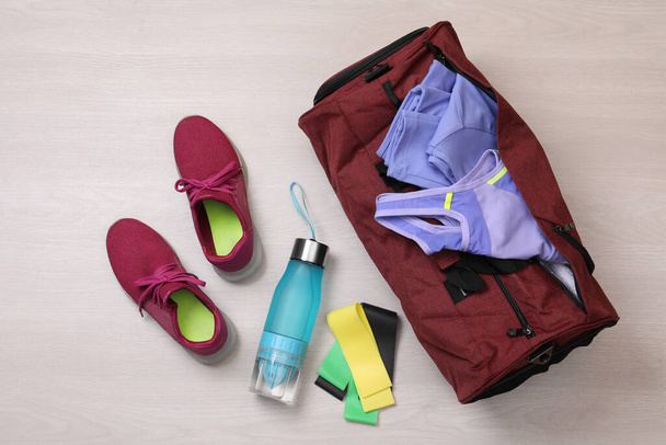Gym bag and sports equipment on wooden background, flat lay - Fotó, kép