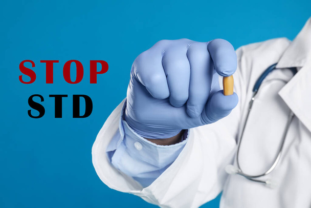 STOP STD. Doctor holding suppository on blue background, closeup - Foto, Imagen