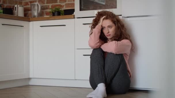 Smutna młoda, biała kobieta siedząca smutna na podłodze w kuchni. Nakręcony aparatem hel RED w rozdzielczości 8K. - Materiał filmowy, wideo